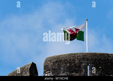 Walisische Flagge über Caerphilly Castle, auf Fahnenmast, der im Wind weht Stockfoto