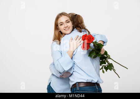 Porträt von einem attraktiven jungen Mann verstecken Blumen von seiner Freundin, bevor er ihr eine Überraschung über Weiß isoliert Hintergrund. Stockfoto