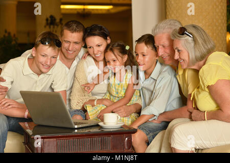 Familie sitzt in der Nähe von Tabelle mit Laptop Stockfoto