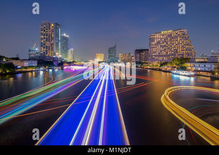 Die Stadt Bangkok bei Sonnenuntergang mit der Abenddämmerung. Die Aufregung der Boote auf dem Fluss mit Beleuchtung. Stockfoto