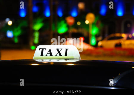 Eine glühende taxi Schild auf dem Dach des Autos in das Licht der