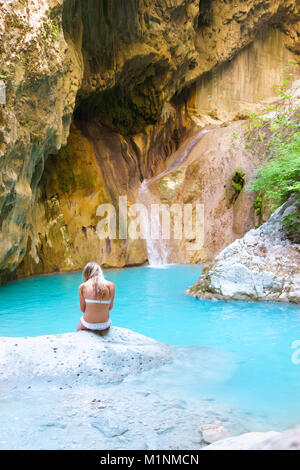Frau, die auf den Stein und das Genießen der natürlichen Wasserfall in den Bergen Stockfoto