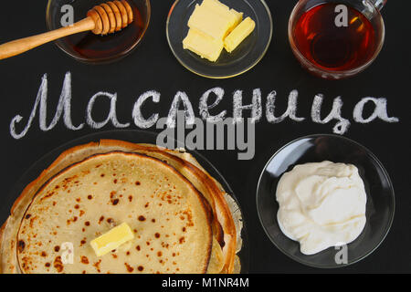 Die Inschrift auf einer Schiefertafel auf Russisch: maslenitsa. Traditionelle ukrainische oder russische Pfannkuchen. Traditionelle Gerichte auf den Urlaub Karneval Maslenit Stockfoto