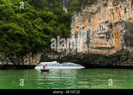 Junge Frauen auf einem Ruderboot außerhalb einer Höhle in der Halong Bay, Vietnam posieren. Die kleinen Inseln und Kalkfelsen Formationen haben sich von der UNESCO zum geschützten Bereich. Stockfoto