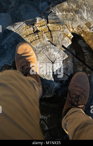 Eine Person mit Hose und Schuhe in natürlichen, warmen Farben, steht auf Holz- Stamm, persönliche Sicht. Konzepte - Mode, Tourismus, Herbst - Winter Stockfoto