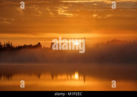 Sonnenaufgang, Morgens Nebel über Kirchsee mit Kloster Reutberg, Sachsenkam, Tölzer Land, Oberbayern, Bayern, Deutschland Stockfoto