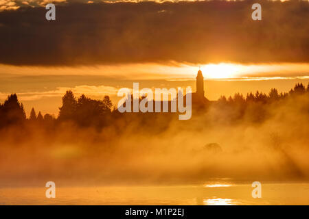 Sonnenaufgang, Morgens Nebel über Kirchsee mit Kloster Reutberg, Sachsenkam, Tölzer Land, Oberbayern, Bayern, Deutschland Stockfoto