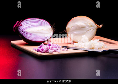 Rote und weiße Zwiebel schneiden und alle auf einem hölzernen unten in schwarzer Hintergrund Stockfoto