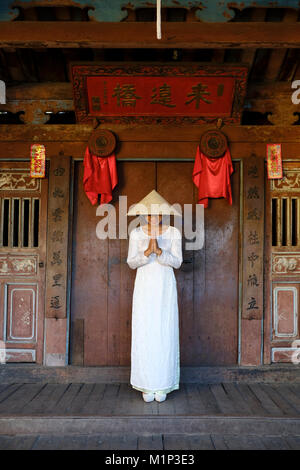 Eine junge Frau in einem Nicht La konische Hut und einem traditionellen Ao Dai Kleid im historischen Zentrum, Hoi An, Quang Nam, Vietnam, Indochina, Südostasien Stockfoto