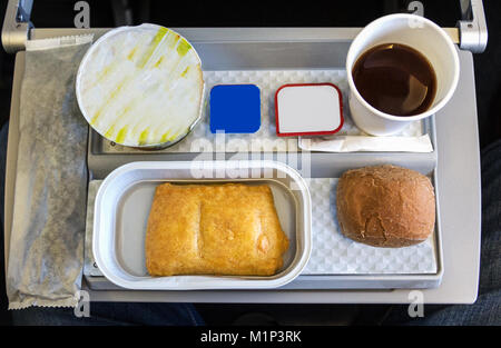 Ein Frühstück mit Kaffee, Butter, Brot und Joghurt auf einem Tablett, an Bord einen kurzen Flug in der Economy Class in Europa. Stockfoto