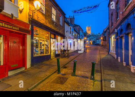 Blick auf den beleuchteten Kathedrale von Lincoln gesehen von den gepflasterten steilen Hügel in der Dämmerung, Lincoln, Lincolnshire, England, Vereinigtes Königreich, Europa Stockfoto