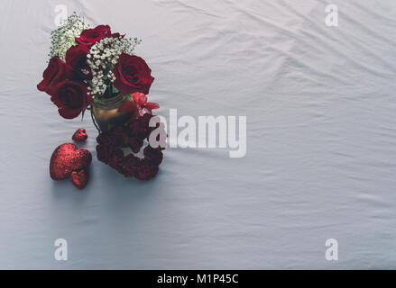 Blick von oben auf die Rosen und mehrere Herzen auf einen weißen Hintergrund mit Text Raum auf der rechten Seite. Stockfoto