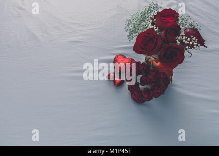 Blick von oben auf die Rosen und mehrere Herzen auf einen weißen Hintergrund mit Text Raum auf der linken Seite. Stockfoto