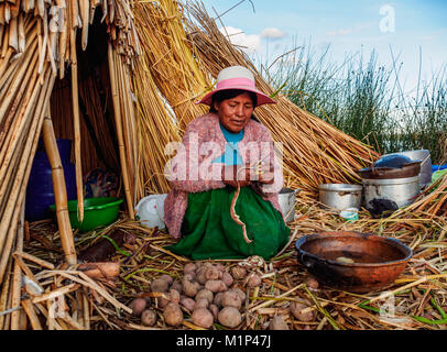 Native Uro Lady kochen, schwimmenden Inseln der Uros, Titicaca See, Region Puno, Peru, Südamerika Stockfoto