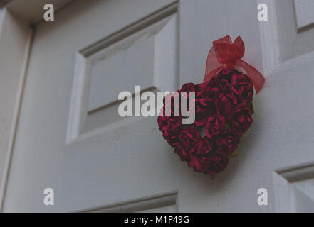 Herz aus mehreren Rosen hängend an einer Haustür von einem niedrigen Winkel betrachten. Stockfoto