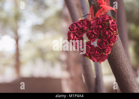 Herz aus mehreren Rosen hängend an einem Ast. Einstellungen ist das Freien und Dead Space auf der linken Seite für Text und Meldungen Stockfoto