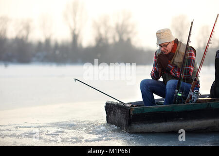 Reifen angler Angeln vom Boot auf Frost Fluss Stockfoto