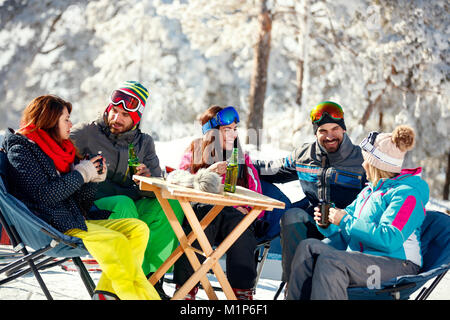Freunde lachen und bringt Kaffee Pause beim Skifahren auf dem Berg zusammen Stockfoto