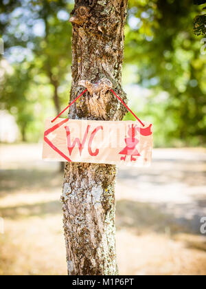 Die toilette Schild hängt am Baum Stockfoto