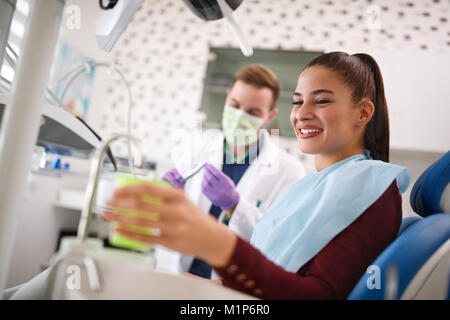 Lächelnd weibliche in der Zahnmedizinischen ambulanten unter Tasse Wasser Stockfoto