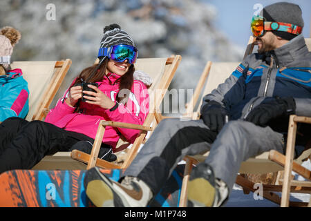 Frau und Mann auf Skifahren im Liegestuhl ausruhen und erfrischend Stockfoto