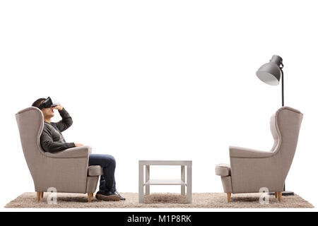 Junge Mann erleben virtuelle Realität durch eine VR-Headset in einem Sessel sitzt auf weißem Hintergrund Stockfoto