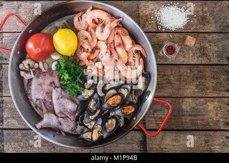 Rohe Meeresfrüchte Produkte in paella Pfanne auf einem Holztisch, Ansicht von oben Stockfoto