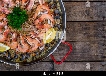 Traditionellen Meeresfrüchte Paella in der Pfanne anbraten, auf einem alten Holztisch, Ansicht von oben Stockfoto