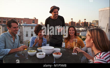 Sechs Freunde an einem Tisch auf einer Dachterrasse mit Lachen, Nahaufnahme Stockfoto