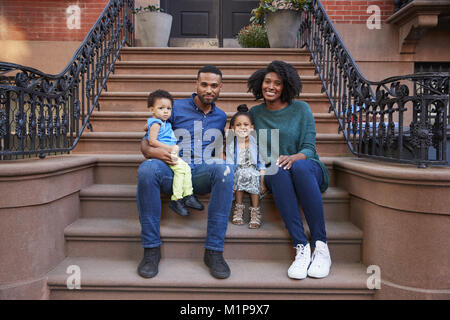 Junge Familie mit Kindern sitzt auf der vorderen Stoops Stockfoto