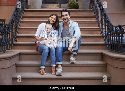 Junge Familie mit Kindern sitzt auf der vorderen Stoops Stockfoto