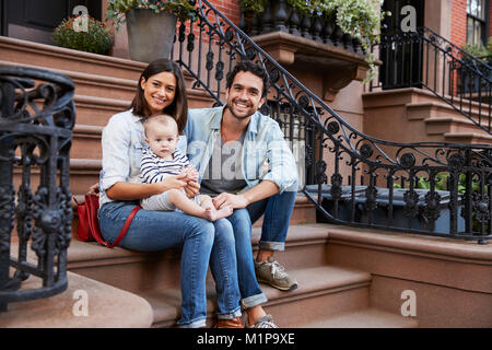 Junge Familie mit Kindern sitzt auf der vorderen Stoops Stockfoto