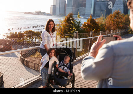 Junge Familie mit zwei Töchtern, die ein Foto auf Steg Stockfoto