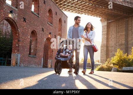 Junge Familie mit einer Tochter, die zu Fuß auf einer Straße Stockfoto