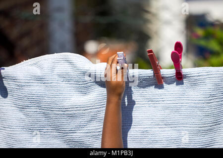 Ein junges Mädchen spielen mit Wäscheklammern und Aufhängen der Wäsche Decke auf eine Wäscheleine im Garten. Stockfoto