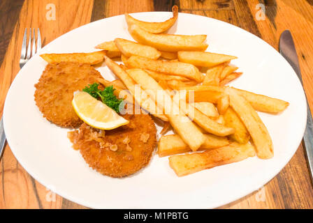 Ein Café das Mittagessen von geräuchertem Schellfisch Fischfrikadellen mit Pommes frites einer Scheibe Zitrone und Petersilie garnieren Stockfoto