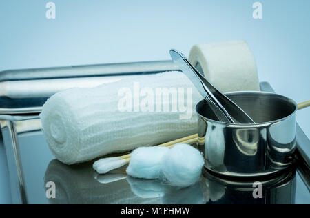 Wundversorgung Abrichten auf Platte aus rostfreiem Stahl. Tupfer mit Alkohol, Wattestäbchen, chirurgische Tape, Pinzette und Bandage entsprechen. Stockfoto