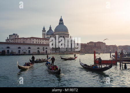 Gondeln in Grand Canal, die Touristen auf Fahrt mit der Basilika von Santa Maria della Salute in der backgroundin Venedig, Italien Stockfoto