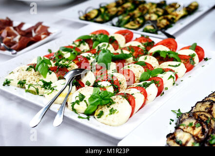 Antipasti Buffet oder Bankett mit Tomate und Mozzarella und frischem Basilikum. Hochzeit oder Party Buffet. Weiße Platten und italienisches Essen. Stockfoto