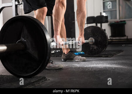 Nahaufnahme eines Fitness Mann zieht die Hantel Vom Boden In der Turnhalle Stockfoto