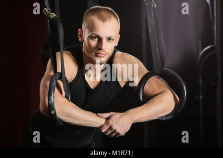 Portrait einer jungen männlichen Athleten mit Gymnastik Ringe In der Turnhalle Stockfoto