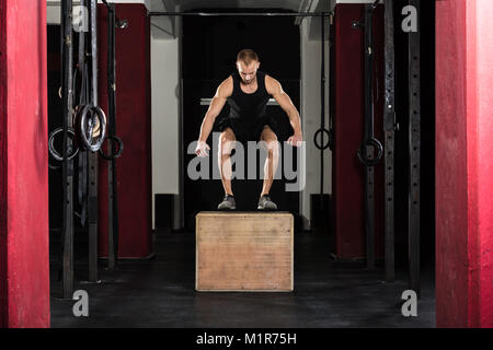 Junge Athlet Mann tut einem Kasten springen Übung In der Turnhalle Stockfoto