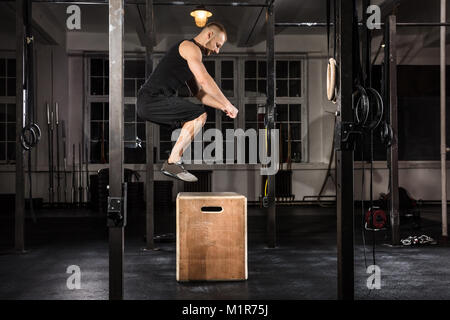 Junge Athlet Mann tut einem Kasten springen Übung In der Turnhalle Stockfoto