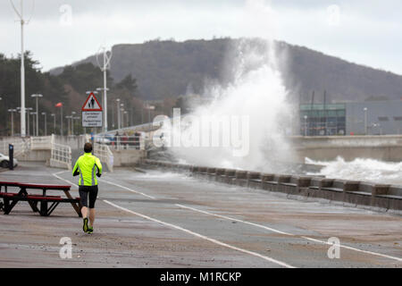 Colwyn Bay, Conwy County, Wales, UK Wetter: Kalt mit Flut und windigem Wetter haben ideale Bedingungen für natürliche Ressourcen Wales Hochwasserwarnungen für die North Wales Küste einschließlich Colwyn Bay. Eine Person, die entlang der Promenade in Colwyn Bay als riesige Wellen Teig der Küstenort mit Hochwasserwarnungen, Conwy County, Wales Stockfoto