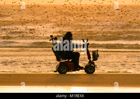 Blackpool, Lancashire, 1. Feb 2018. UK Wetter. Nach einer windigen und eiskalt Tag, eine Mobilität scooter Köpfe heraus für ein scoot entlang der im goldenen Glanz eines Sonnenuntergangs streicheln die Ufer auf Blackpools Strandpromenade in Lancashire. Credit: cernan Elias/Alamy leben Nachrichten Stockfoto