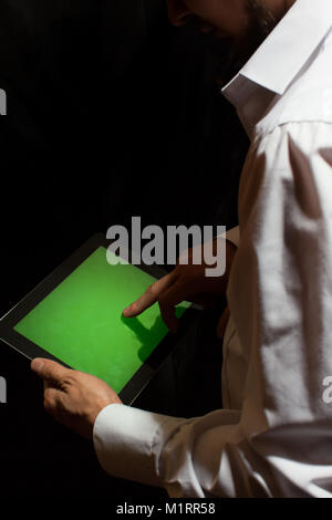 Der Mann in den Händen einer Tablette mit einem grünen Bildschirm Stockfoto