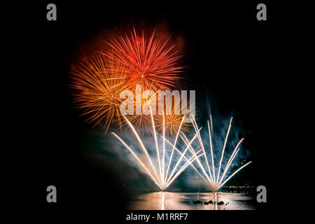 Die hellen und farbenfrohen Feuerwerk vor einem schwarzen Nachthimmel. Feuerwerk für das neue Jahr. Schöne bunte Feuerwerk auf der städtischen See für Feier Stockfoto