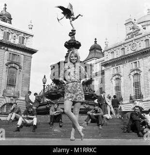 Ein Modell stellt in einem Mini Dress im Freien in Londons Piccadilly in der Nähe der Statue des Eros in ca. 1968 tragen eine bunte mini-kleid. Foto von Tony Henshaw Stockfoto