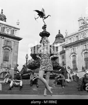 Ein Modell stellt in einem Mini Dress im Freien in Londons Piccadilly in der Nähe der Statue des Eros in ca. 1968 tragen eine bunte mini-kleid. Foto von Tony Henshaw Stockfoto