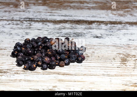 Trockene Wacholderbeeren auf einem alten weißen Holztisch Stockfoto